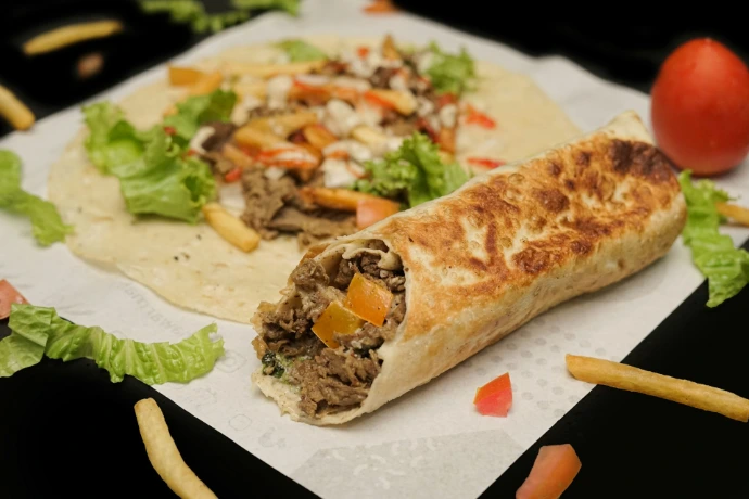 A burrito with meat, cheese, and lettuce on it